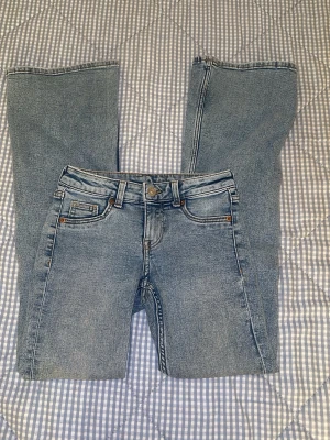 Blå jeans från H&M Divided, storlek 32 - Snygga ljusblå jeans från H&M Divided i storlek 32. Klassisk femficksmodell med raka ben och normal passform. Jeansen har knapp och dragkedja framtill samt bälteshällor. Tillverkade i bomull med jeansmaterial och har en stilren look.