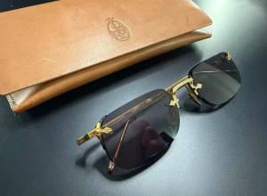 Jacques Marie Mage solglasögon Fonda - Jacques Marie Mage solglasögon Modell, Fonda 29 av 300 STORLEK: ÖGON: 52 BROGGAN: 21 SKALMAR: 141 FÄRG: "Guld" - Mörkguld Båglösa solglasögon med skalmar och näsbrygga tillverkade av fint graverat japanskt beta-titan. Acetater upp till 10 mm tjocka och lätta. Linser med 100 % UVA-UVB-skyddsfilter och antireflexbeläggning. Begränsad upplaga om 300 stycken, handgjorda i Japan. Unisex solglasögon Begagnade