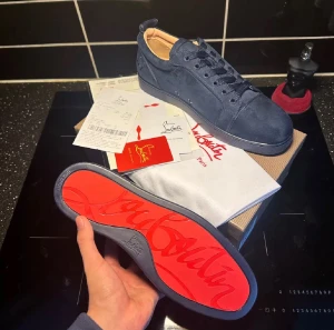  Christian Louboutin - Säljer ett par mörkblå sneakers från Christian Louboutin med ikonisk röd sula och snygg snörning. Skorna är tillverkade i mocka och har en rund tå. Perfekt för dig som vill sticka ut med exklusiva detaljer och lyxig design. Mer bilder finns hör av er vid frågor. Priset är diskutertbart 