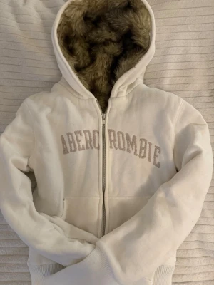 Fur päls zip up hoodie med foder abercrombie & fitch - Vit Abercrombie & fitch fur zip up hoodie!                    Päls i hela hoodien förutom armarna!                               Mycket bra skick!                                                   Storlek M men passar en XS eftersom den är slimfit!