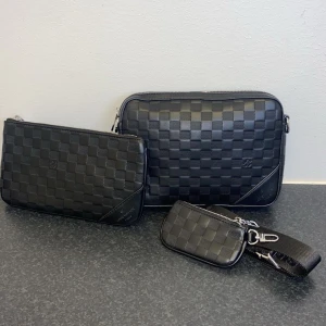 Svart rutigt väska-set – helt ny 50% rabbat  - Helt ny svart väska-set med klassiskt rutigt mönster. Inkluderar axelrem och liten pouch. Aldrig använd, i perfekt skick och redo för ny ägare.