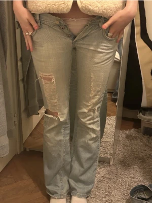 Ljusblå bootcut jeans med slitningar - Säljer ett par ljusblå bootcut lowwaisted jeans! Köpta här på plick med passade inte tyvärr.💕midjemåttet är 31, innerbenslängden 80! (Inte mina bilder). Två små hål i rumpan men inget som syns när jeansen sitter på.(se sista bild)