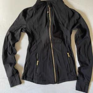 Svart träningsjacka från Lululemon - Lululemon define jacket. Storlek 2 som motsvarar xxs/xs. Guldiga dragkedjor och ett svart mjukt tyg. Använd fåtal gånger/som ny✅. Öppen för prisförslag!