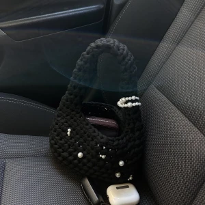Svart stickad handväska med pärlor - Unik svart handväska från Hooked by Tilda!  Väskan har creme vita glansiga pärlor och har en gullig knappfäste!   Mått: 10x22x26 Pris: 169kr  Är du intresserad? Kika in på min Vinted för att se vad som finns till salu, eller skicka ett DM för en personliga beställningar! 
