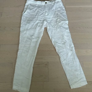 Vita linnebyxor med rak passform - Snygga vita linnebyxor med klassisk rak passform och fickor i sidorna. Perfekta för varma dagar och ger en fräsch och stilren look. Byxorna har knapp och dragkedja framtill samt bälteshällor. Är knappt använda och inga fel på