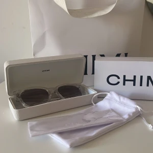 Clear CHIMI solglasögon - Snygga solglasögon från CHIMI med transparent båge och mörka, fyrkantiga linser. Kommer med originalfodral och vit tygpåse. Perfekt accessoar för att lyfta din stil och skydda ögonen mot solen. Använt enstaka gång men inga repor eller tecken på andvändning, bara att höra av sig vid frågor💕