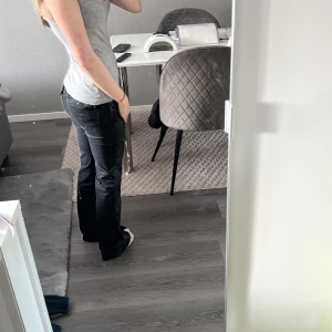 Svarta bootcut jeans med låg midja - Säljer ett par svarta jeans med bootcut-modell och låg midja. Jeansen har klassisk femficksdesign och är tillverkade i ett mjukt denimtyg. Snygg passform som sitter tajt upptill och släpper ut vid bensluten.