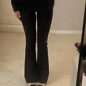 Svarta lågmidjade bootcut kostymbyxor gina tricot  - Säljer ett par svarta kostymbyxor med bootcut-snitt och låg midja. Byxorna har klassiska pressveck och bälteshällor, vilket ger en clean och stilren look. Perfekta om du vill ha en snygg siluett och lite utsvängda ben.💓💓