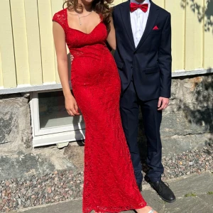 Röd lång spetsklänning - Säljer en röd långklänning med smickrande passform. Klänningen har vackra spetsdetaljer över hela tyget, korta ärmar och dragkedja i ryggen. Perfekt för bal eller sittning. Materialet är spets men rätt stretchig. Använd 1 gång. Från JW.