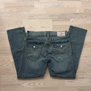 True Religion jeans Geno💙 - Säljer ett par klassiska blå herrjeans från True Religion med tydliga kontrastsömmar och ikoniska fickdetaljer med lock och knapp. Jeansen har rak passform och normal midja. Helt nya utan tag. 