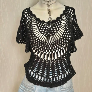 Svart virkad topp med pärlor - Unik svart virkad topp med kort ärm och snyggt genombrutet mönster. Toppen har små pärlor insydda längs nederkanten för extra bling. Perfekt att styla över ett linne eller bikini. Den har en loose passform och är riktigt luftig och cool.