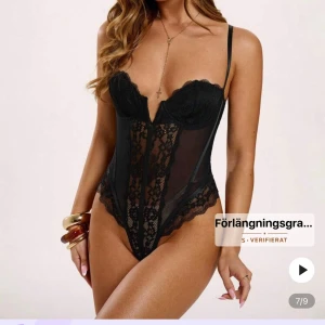 Svart spetsbody - Säljer en svart body med tunna axelband, djup v-ringning och vackra spetsdetaljer framtill. Toppen har meshpaneler på sidorna och spetskant längs bysten och nederkanten. Perfekt att styla med jeans eller kjol för en trendig look. 