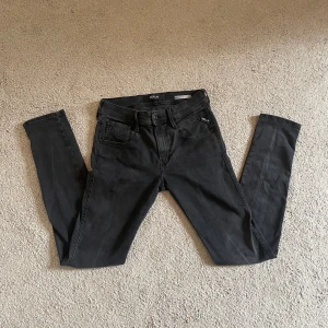 Replay Anbass svarta slim jeans  - Svarta jeans från Replay, modell Anbass med slim fit. Klassisk femficksdesign, svarta sömmar och diskret Replay-logga vid fickan. Jeansen har en smal passform och är tillverkade i stretchigt denim för extra komfort. 29/32