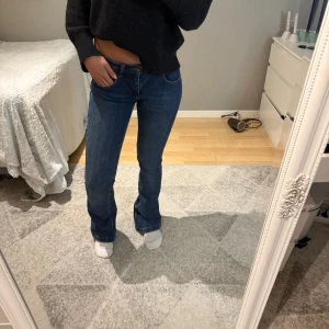 Blå bootcut jeans från Selected - Säljer ett par mörkblåa low waist bootcut jeans med knappfickor från Subdued i storlek 38. Jag skulle nog säga att jeansen är väldigt små i storleken då jag vanligtvis brukar ha storlek 34 i byxor. Jag är 162cm  och trampar på jeansen så längden skulle passa någon längre.