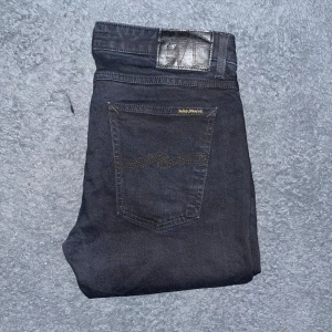 Nudie Jeans Skinny Lin - Svarta Skinny Lin jeans från Nudie Jeans med smal passform och klassisk femficksdesign. Tillverkade i 98% bomull och 2% elastan för en stretchig känsla. Snygga detaljer med svarta sömmar och diskret logga på bakfickan. Midja 40cm, längd 94cm. Ifall det inte finns någon bild i annonsen där jag bär plaggen jag säljer så är det för att jag ej kan ha storleken heller passformen, så kolla måtten för storlek och googla på modellnamnet för passform 😉