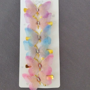 Fjärilsformade hårspännen  - Ny.Säljer ett set med fem fjärilsformade hårspännen i pastellfärger som rosa, lila och blå. Spännena har guldfärgade detaljer och glittriga stenar i mitten för extra bling. Perfekt accessoar för att piffa upp frisyren med en söt och färgglad touch.