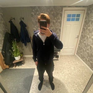 Mörkblå Kashmir hoodie från Polo Ralph Lauren - Mörkblå hoodie från Polo Ralph Lauren med dragkedja och huva. Klassisk grön broderad logga på bröstet. Skön passform och mjukt material, perfekt för kyligare dagar. Snygg och enkel att matcha med det mesta. Det är en kashmir hoodie. Inget fel och den passar perfekt 