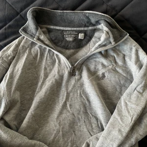 Grå half zip tröja från Polo Ralph Lauren - Snygg grå långärmad tröja från Polo Ralph Lauren med half zip och klassisk broderad logga på bröstet. Mjuk bomullskänsla och hög krage som går att vika ner. Perfekt för lager-på-lager och chill vardagsstil. Original pris - 1800 kr