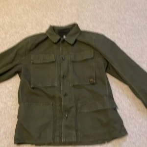 Olivgrön overshirt från G-Star RAW XL - Snygg olivgrön overshirt från G-Star RAW i storlek XL. Jackan har fyra stora fickor framtill, klassisk krage och knäppning med knappar. Tillverkad i bomull, perfekt för lager-på-lager och streetwear-vibe. Köpt för 1200kr. Är knappt använd. Har bara använt den vid två tillfällen, den är som ny. 