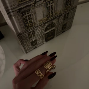 Två chunky guldiga ringar - Säljer ett set med två chunky ringar i guldton. Alla ringar har olika former och texturer – en med vågig design, en med hamrad yta och en med små nitar. Perfekta för att ge din look en cool och trendig touch.