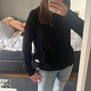 Svart stickad tröja från Oddmolly  - Säljer en svart stickad tröja från odd Molly med grovt kabelstickat mönster. Tröjan har lång ärm, rund hals och ribbade muddar. Perfekt för lager på lager under kyliga dagar.