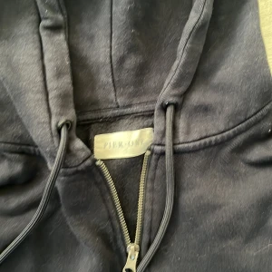 Svart hoodie med dragkedja från Pier One - Klassisk svart hoodie från Pier One med dragkedja framtill och huva med snörning. Tröjan har två fickor fram och är tillverkad i mjuk bomullsmix. Perfekt för chill dagar eller när du vill ha en enkel och stilren look.