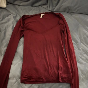 Vinröd långärmad topp med v-ringning - Säljer en vinröd långärmad topp från H&M med snygg v-ringning och smal passform. Toppen är i mjuk bomull och har en enkel, stilren look som funkar till många outfits.