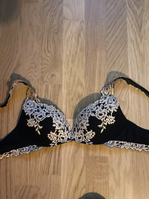 Intimissimi bh - Säljer en marin blå bh från intimissimi med vacker spets och blommigt mönster i vitt. Bh har en feminin design med spetsdetaljer längs kanterna och axelbanden. Strl 75b