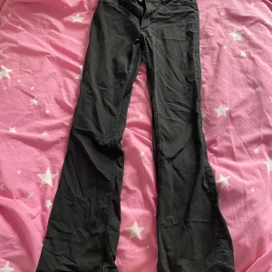 Svarta flare jeans från H&M - Säljer ett par svarta flare jeans från H&M i storlek 164. Byxorna har låg midja och utsvängda ben, sitter snyggt över höften och låren. Klassisk femficksmodell med knapp och dragkedja. Perfekta om du gillar en trendig siluett!