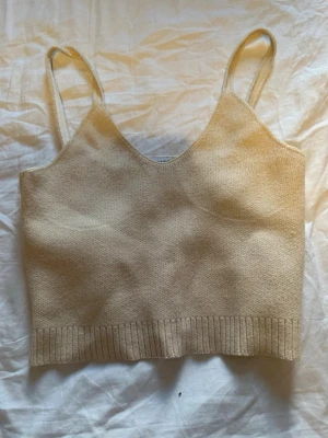 Beige stickad linnetopp från Zara - Säljer en beige stickad linnetopp från Zara i storlek M. Toppen har smala axelband, v-ringad hals och ribbad kant nedtill. Perfekt för varma dagar och enkel att matcha med jeans eller kjol. Materialet är mjukt och ger en chill vibe.
