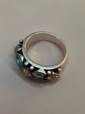Ring med stenar - En silver ring med blå och klara stenar. Bra skick men lite repig ibak. Vet inte om den klarar av vatten