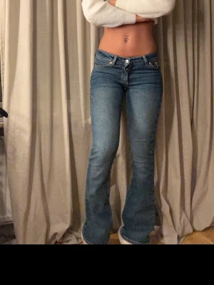 Blå bootcut jeans lågmidjade - Snygga blå jeans med bootcut och låg midja. Klassisk femficksmodell med ljus kontrastsöm på bakfickorna. Jeansen har en smickrande passform och är tillverkade i jeansmaterial med lätt stretch. Perfekta för dig som gillar retrovibbar och vill ha en cool siluett.