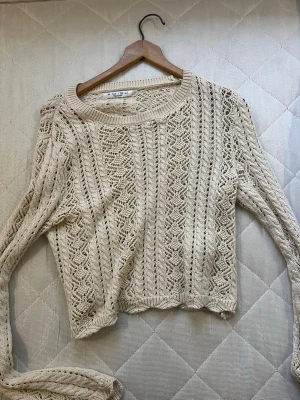 Beige stickad tröja från Amisu - NEWYORKER  - Säljer en beige stickad tröja från Amisu med snyggt hålmönster och rund hals. Tröjan har långärmade ärmar och är perfekt för lager-på-lager. Den har en loose passform och är riktigt skön att ha på sig under kyliga dagar.