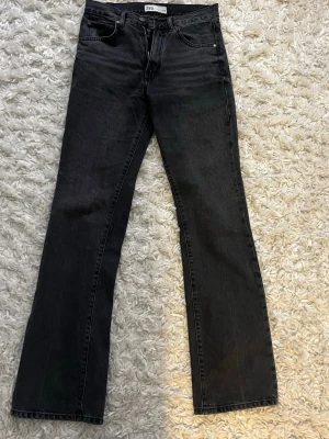 Svarta bootcut jeans från Zara - Säljer ett par svarta jeans från Zara med bootcut-snitt och medel midja. Klassisk femficksmodell med dragkedja och knapp framtill. Jeansen har en snygg mörk tvätt.