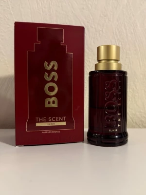BOSS The Scent Elixir Parfym - 🟩Cirka halva flaskan kvar!                                  Denna berusande ambraiga läderaktiga doft antänds av glödhet Pimento, som skapar en komplex, kryddig doft som utstrålar karisma. I hjärtat ger frestande Lavandin absolute - från Provence - balans till den eldiga toppnoten, medan jordig kaledonisk sandelträ ger denna herrparfym en mjuk kant. Elixir är skapad med ansvarsfullt framställda, naturliga ingredienser och är en signaturdoft som håller hela dagen.