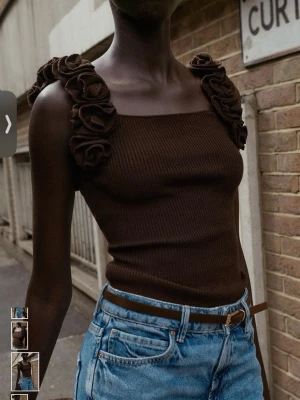 Brun ribbad linnetopp med volangaxel. Zara - Säljer en brun ribbad linnetopp med breda axelband dekorerade med volanger. Toppen har en fyrkantig halsringning och är figurnära i passformen. Materialet är mjukt och stretchigt, perfekt att styla med jeans eller kjol. Zara