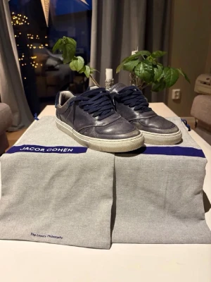 Jacob choën skor - Säljer ett par stilrena Jacob Cohën sneakers i mörkblått skinn/mocka. Väldigt snygga och bekväma skor av hög kvalitet – perfekta till både jeans, chinos och mer uppklädda outfits.  ✔ Äkta Jacob Cohën ✔ Premium material ✔ Bekväm sula ✔ Klassisk och tidlös design