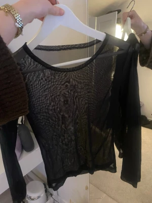Svart mesh långärmad topp - Säljer en svart mesh topp med lång ärm och rund halsringning. Toppen är helt genomskinlig och har en slim passform som sitter snyggt mot kroppen. Perfekt att styla lager på lager eller med ett snyggt linne under. Står inget på tröjan men passar mig som har S. Den är aldrig använd så mycket bra skick. Hör av er för fler frågor💗💗