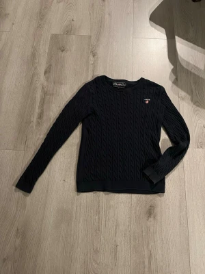 Mörkblå kabelstickad tröja Polo Club - Säljer en mörkblå kabelstickad tröja från Polo Club Saint Vincent. Tröjan har rund hals, lång ärm och ett broderat Polo Club-emblem på bröstet. Klassisk och stilren modell som passar perfekt till jeans eller kjol.