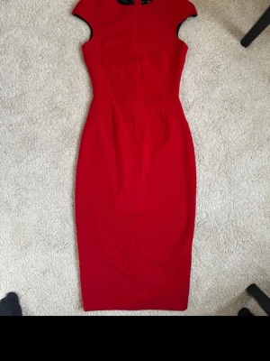 Röd långklänning från Zara Basic - Snygg röd långklänning från Zara Basic med figurnära passform och korta ärmar. Klänningen har en markerad midja och en lång svart dragkedja baktill som ger en cool kontrast. .