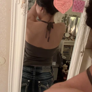 Brun/grön halterneck med Betty Boop-tryck - Säljer en brun/grön halterneck med v-ringning och tryck av Betty Boop på framsidan. Säljer även Miss me shortsen jag har på mig i min nästa annons. Toppen är från märket ”att” i strl S. 