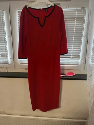 Red Midi Dress with Black Trim – SHEIN – Size S (EU 36) - Elegant red midi dress from SHEIN with black contrast trim. Features a flattering V-style neckline, 3/4 sleeves, and a hidden zip at the back. The dress has a clean, minimalist look that works well for both everyday wear and more formal occasions. Worn only a few times and in very good condition – no stains or damage. Comfortable fabric with a nice drape. Details: Brand: SHEIN Size: S (EU 36 / US 4) Color: Red with black trim Length: Midi Sleeves: 3/4 length Closure: Back zipper Condition: Very 