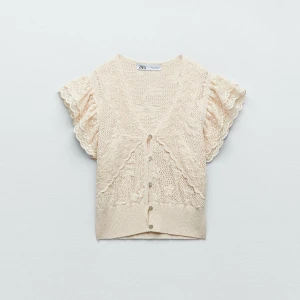 Beige spetsblus från Zara - Supersöt beige blus från Zara med korta puffärmar och spetsdetaljer. Blusen har v-ringning, knappar framtill och är stickad med blommönster. Använd 1 gång