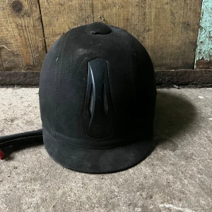 Svart ridhjälm Equipage 52-54 - Säljer en svart ridhjälm från Equipage i storlek 52-54. Hjälmen har en matt yta med mockakänsla, justerbar passform och snygg svart detalj framtill.