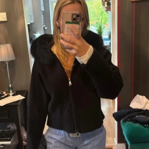 Svart pälsjacka med huva - Säljer en svart pälsjacka med fluffig huva och dragkedja framtill. Jackan har en loose passform och är långärmad med ribbade muddar. Perfekt för dig som vill ha en mysig och stilren look under höst och vinter. Fråga om du vill ha fler bilder!