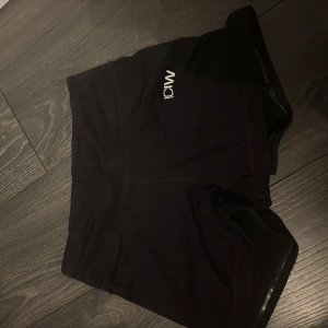 Svarta träningstights shorts från ICANIWILL - Svarta tighta träningstights shorts från ICANIWILL med diskret logga framtill. De är höga i midjan och gjorda i ett stretchigt syntetmaterial som sitter skönt på kroppen. Perfekta för gymmet eller löprundan.
