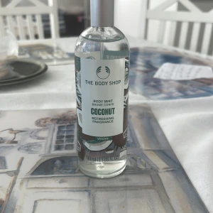 Coconut Body Mist 100ml - Fräsch body mist med kokos från The Body Shop. Vegansk formula och 100 ml flaska – perfekt att ta med i väskan för en snabb uppfräschning när som helst.