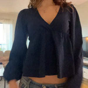 Mörkblå  blus med v-ringning och puffärm - Säljer en mörkblå topp med puffärmar. Köpt från Nelly i storlek 34
