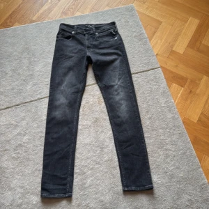 Svarta Wallys Replay jeans skinny fit - Säljer ett par svarta Replay jeans med skinny passform. Jeansen har klassisk femficksdesign, dragkedjegylf och Replay-logga på fickan. Materialet är stretchigt jeans och färgen är tvättad svart med lätt slitning för en cool look.