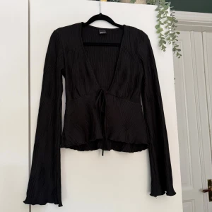 Svart topp - Svart långärmad topp med knytning i fram.